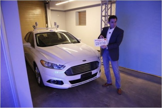 Mark Fields, CEO de Ford, pose avec la voiture autonome Fusion dans le laboratoire de recherche du groupe,  Palo Alto, en Californie. (crdit : Ford)